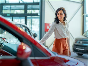 Woman looking a new car in showroom