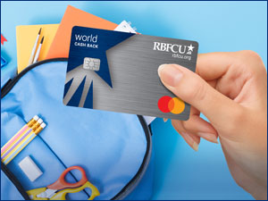 Person holding RBFCU World Cash Back Mastercard credit card while back-to-school shopping