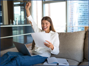 Woman raises fist triumphantly while reviewing paperwork