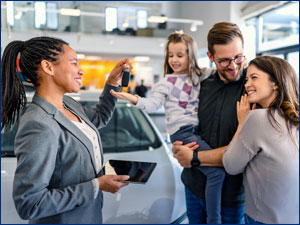 man and woman talking to car salesperson