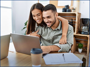 man and woman sitting at a table and looking at laptop screen