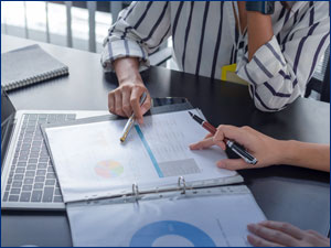 two people looking at graph charts in binder