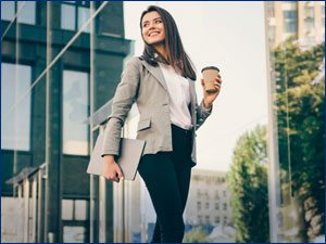 woman holding coffee and laptop walking in the city