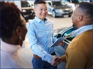 Man and woman buying a car from car salesman