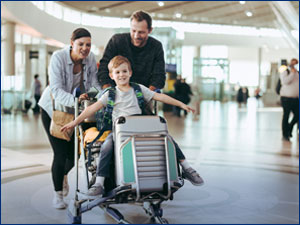 Woman and man push boy and suitcases on a luggage cart