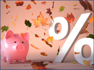 autumn leaves falling on a piggy bank next to a percentage sign