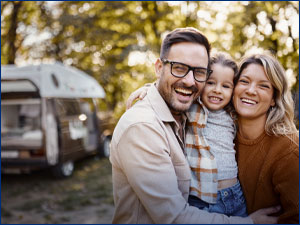 man, woman and child in front of an RV hugging and smiling at camera