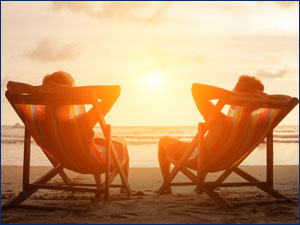 two people sitting along the beach watching the sunset