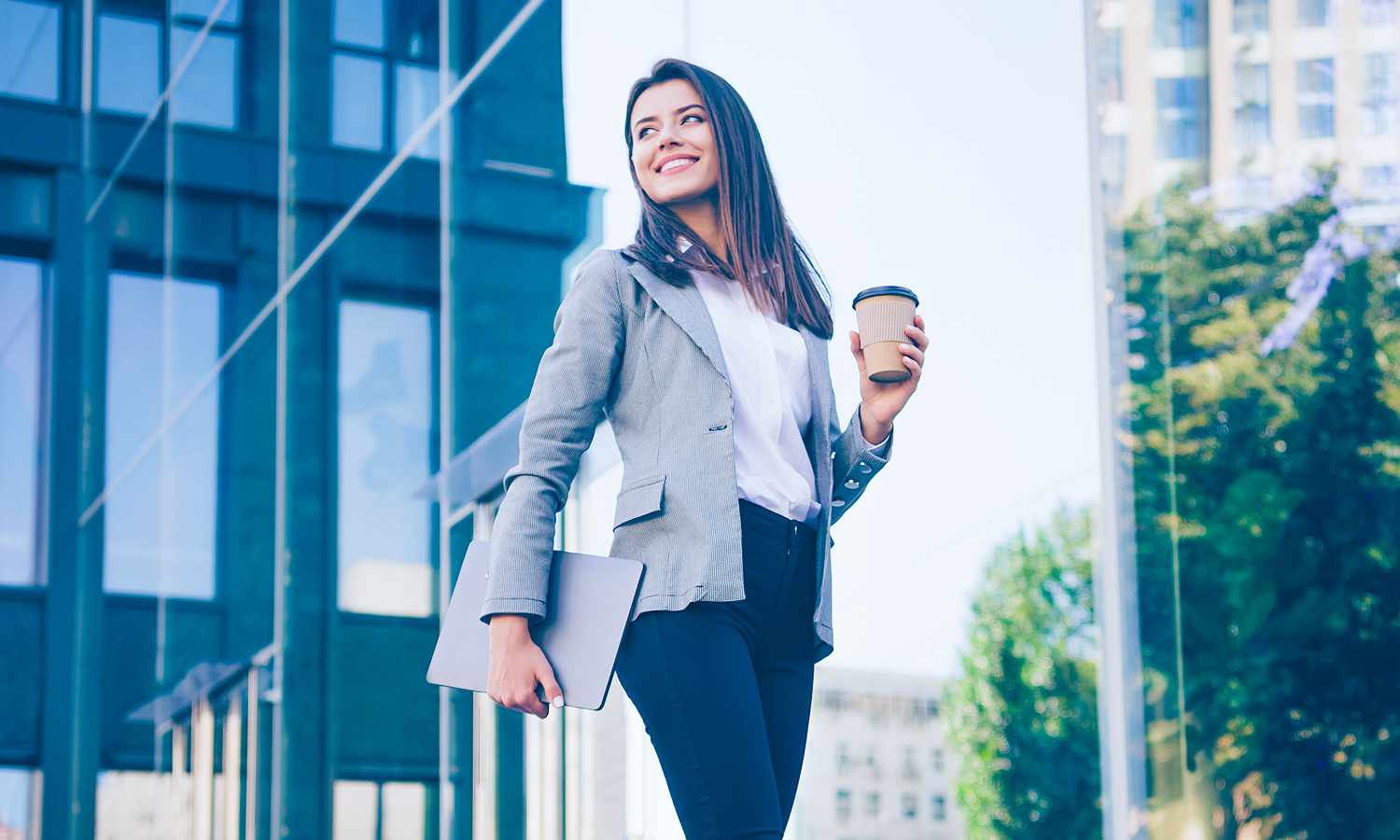 Woman holding laptop and coffee in hands