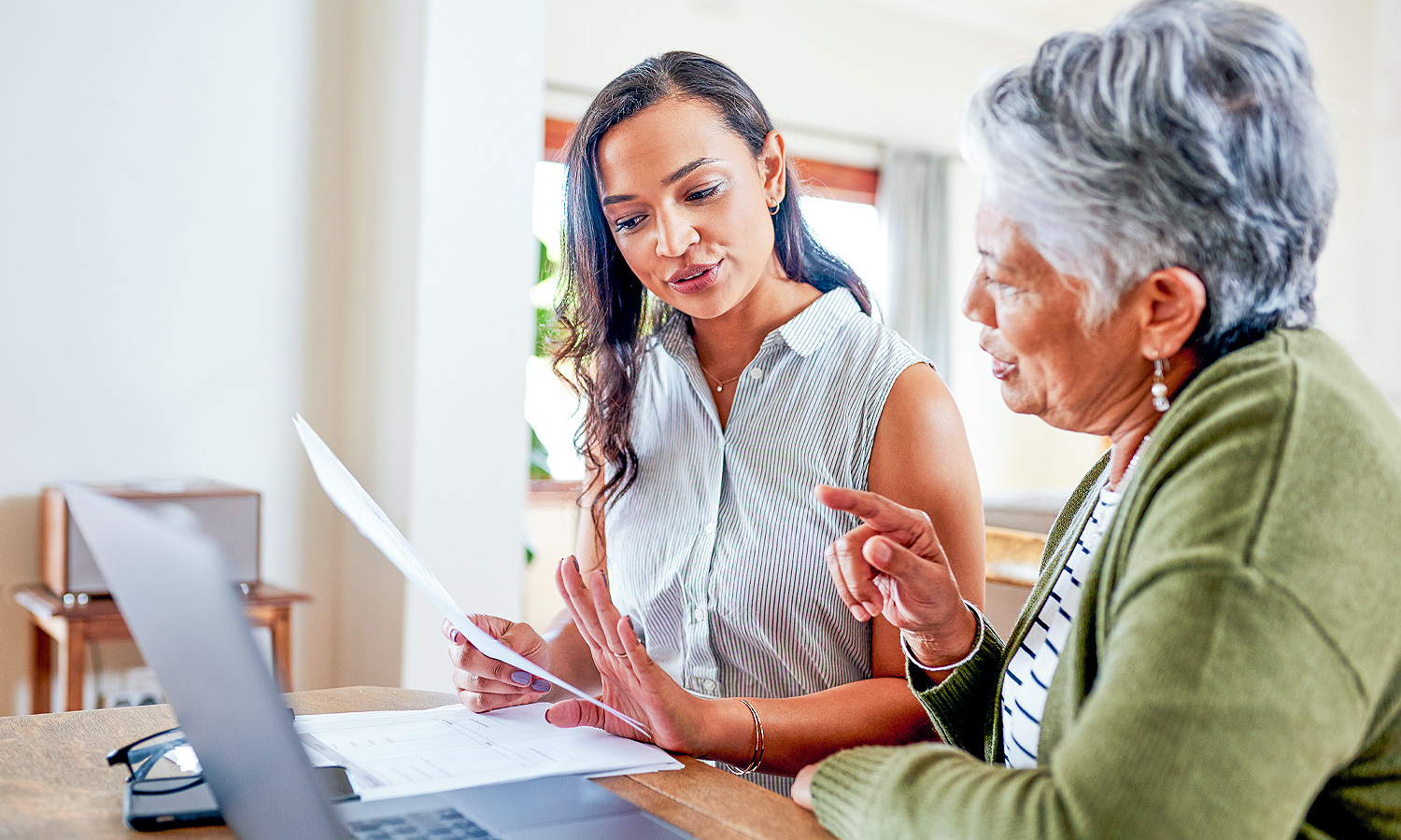 Two women reviewing paperwork while sitting at a table.