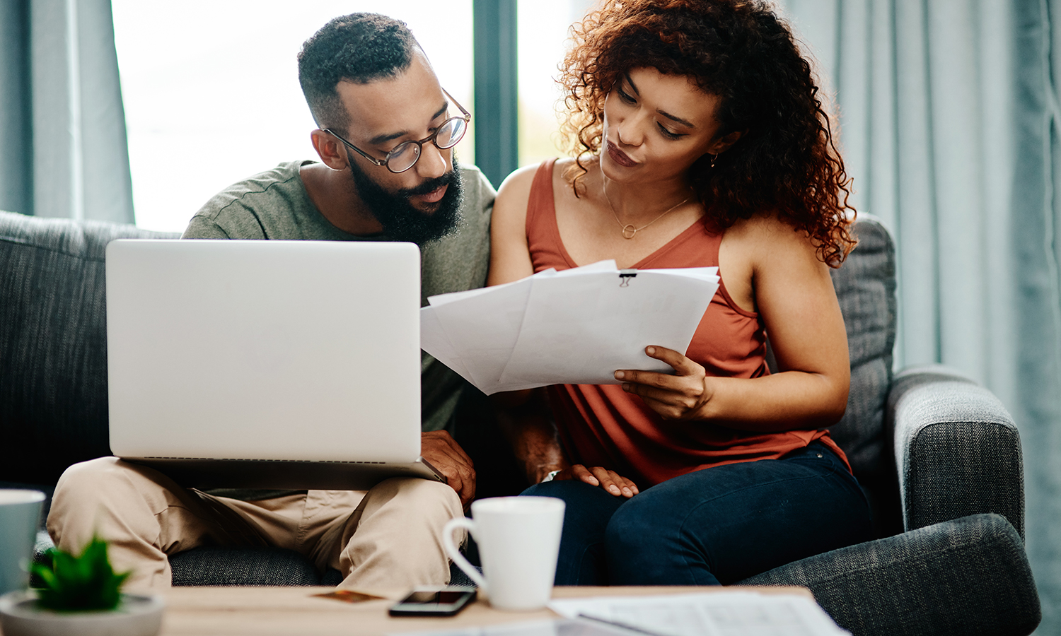 Man and women reviewing financial documents with laptop and calculator nearby