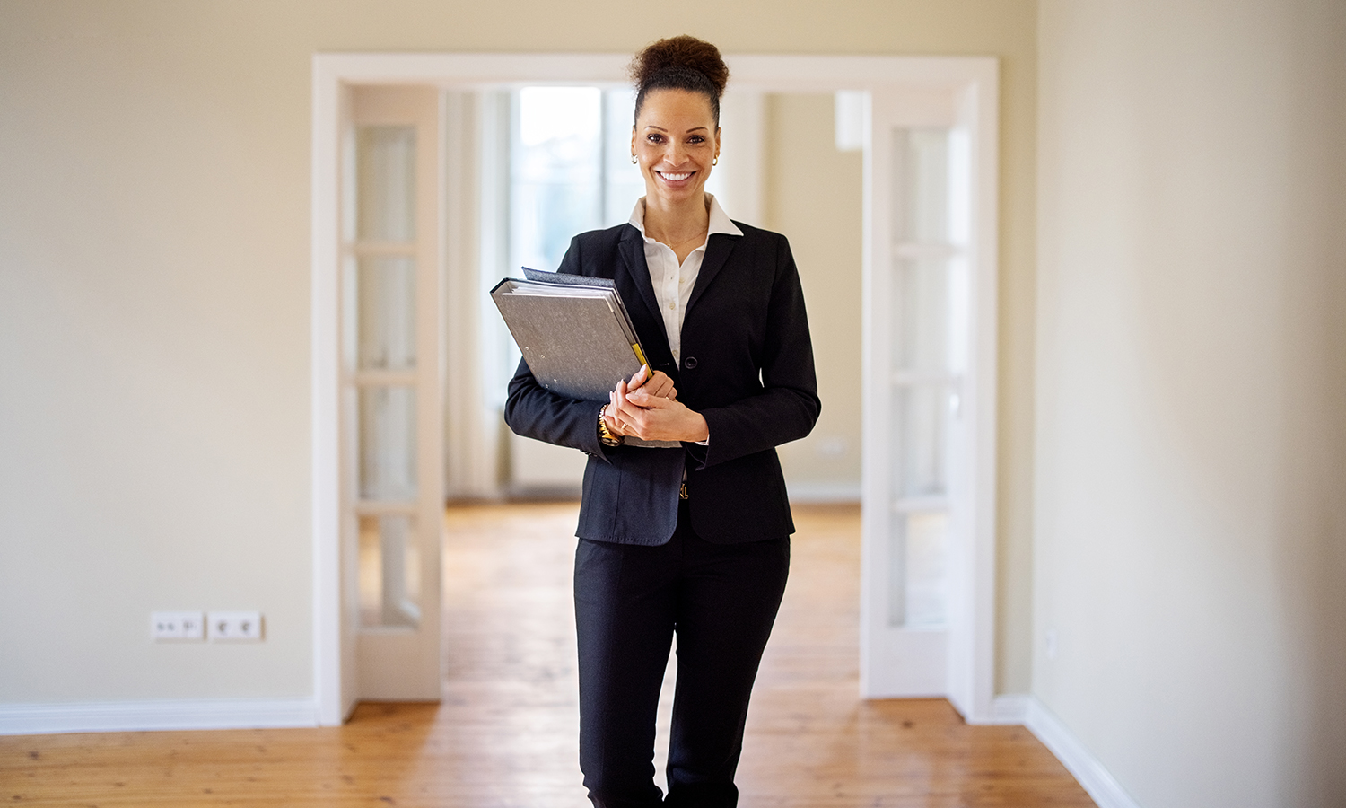 Woman real estate agent holds files while standing in empty house