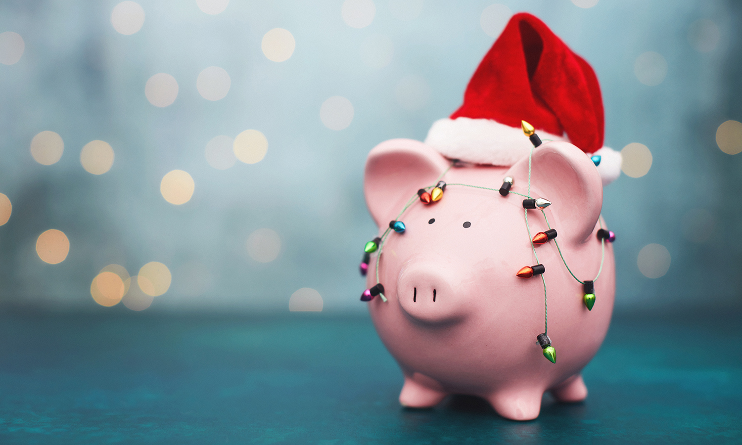 Piggy bank wearing a Santa hat and covered with holiday lights