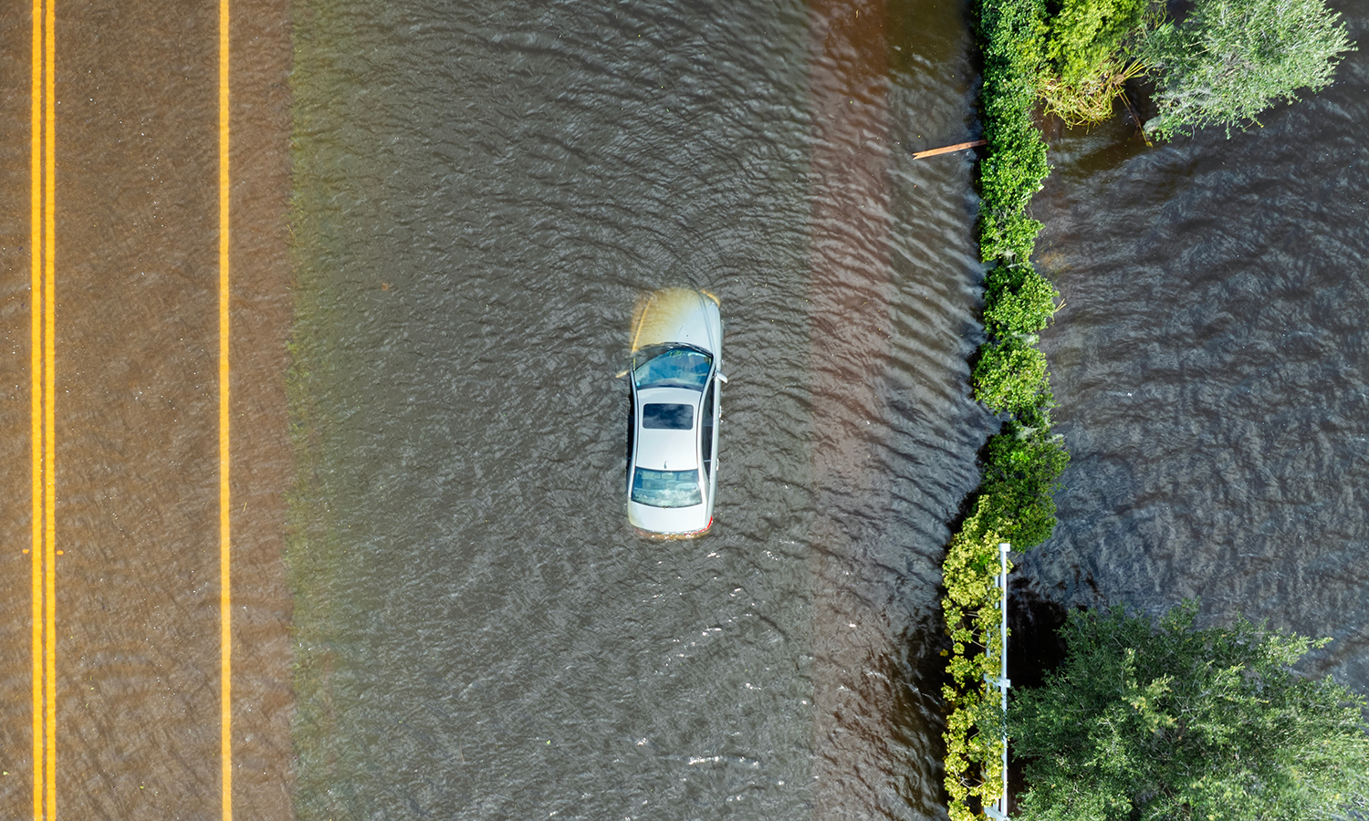 Car sitting in floodwaters covering road