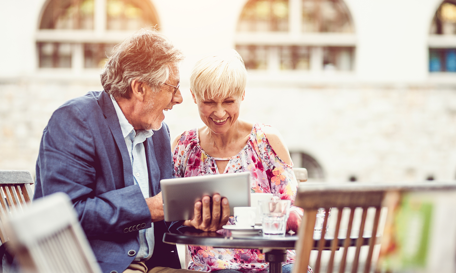 Older couple reviews information on tablet while dining outside