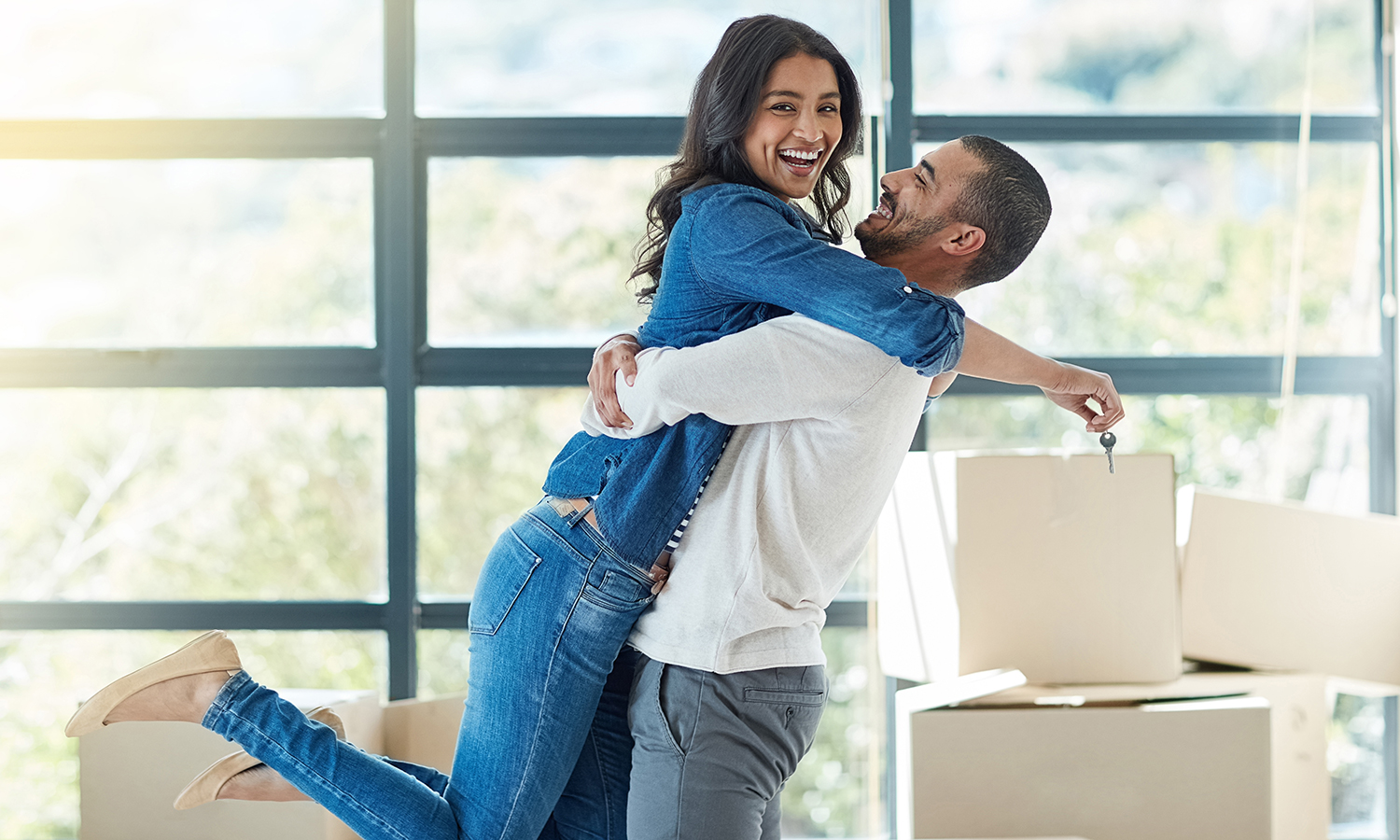 Man lifting woman into the air during hug while celebrating moving into new home