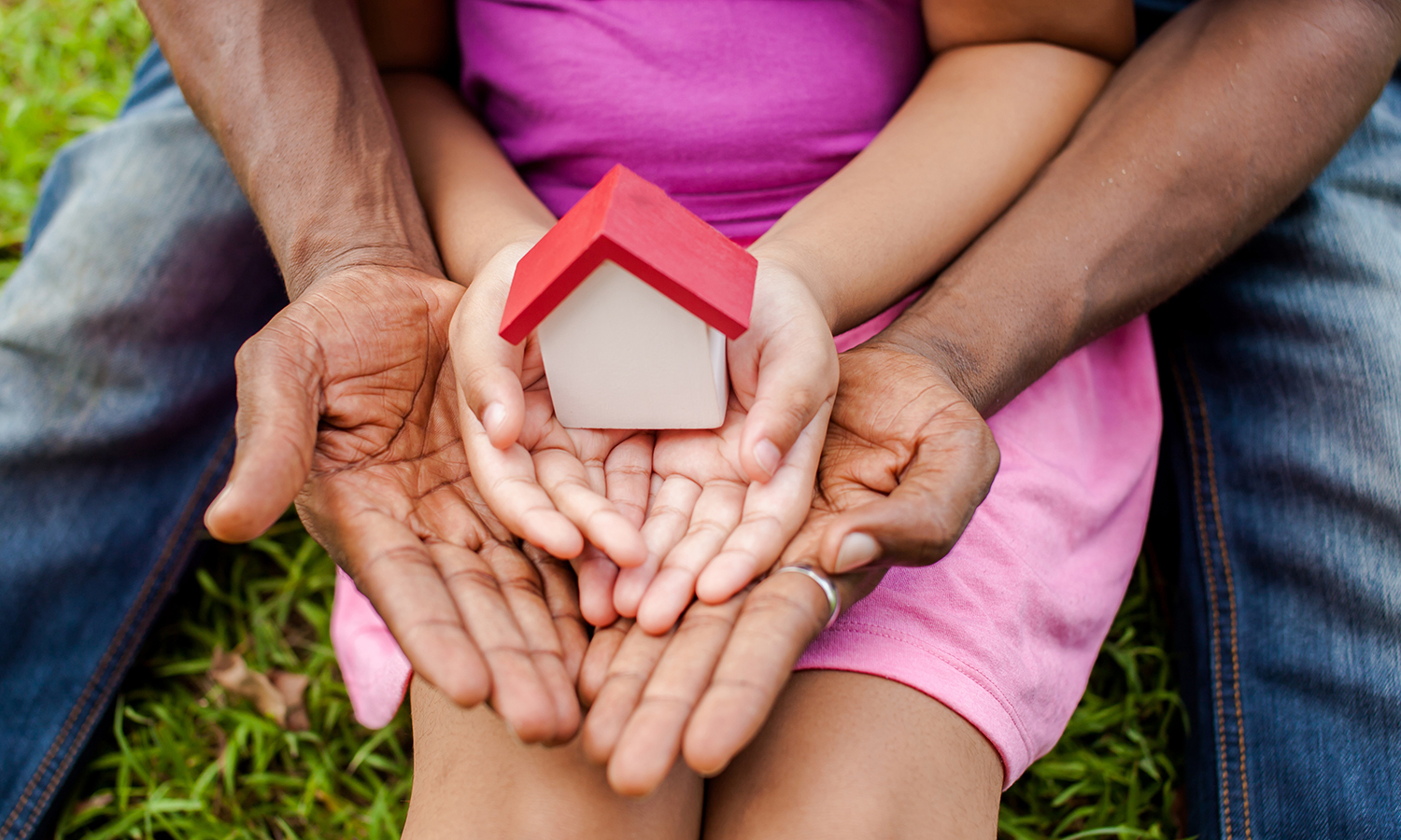 Man and child's hands holding small toy house