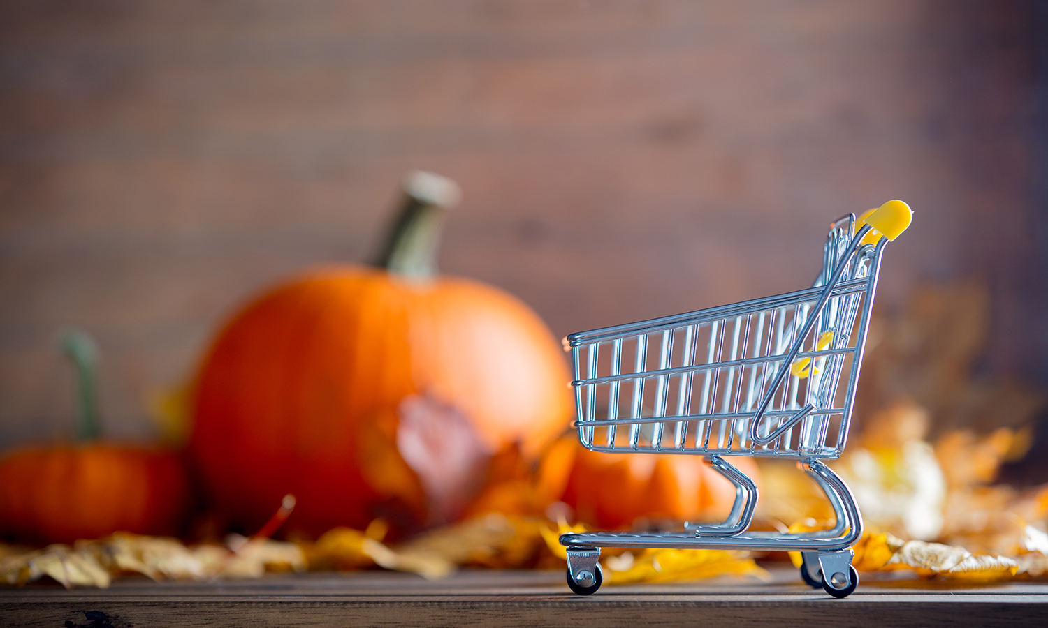 Small shopping cart with pumpkins and fall leaves in the background