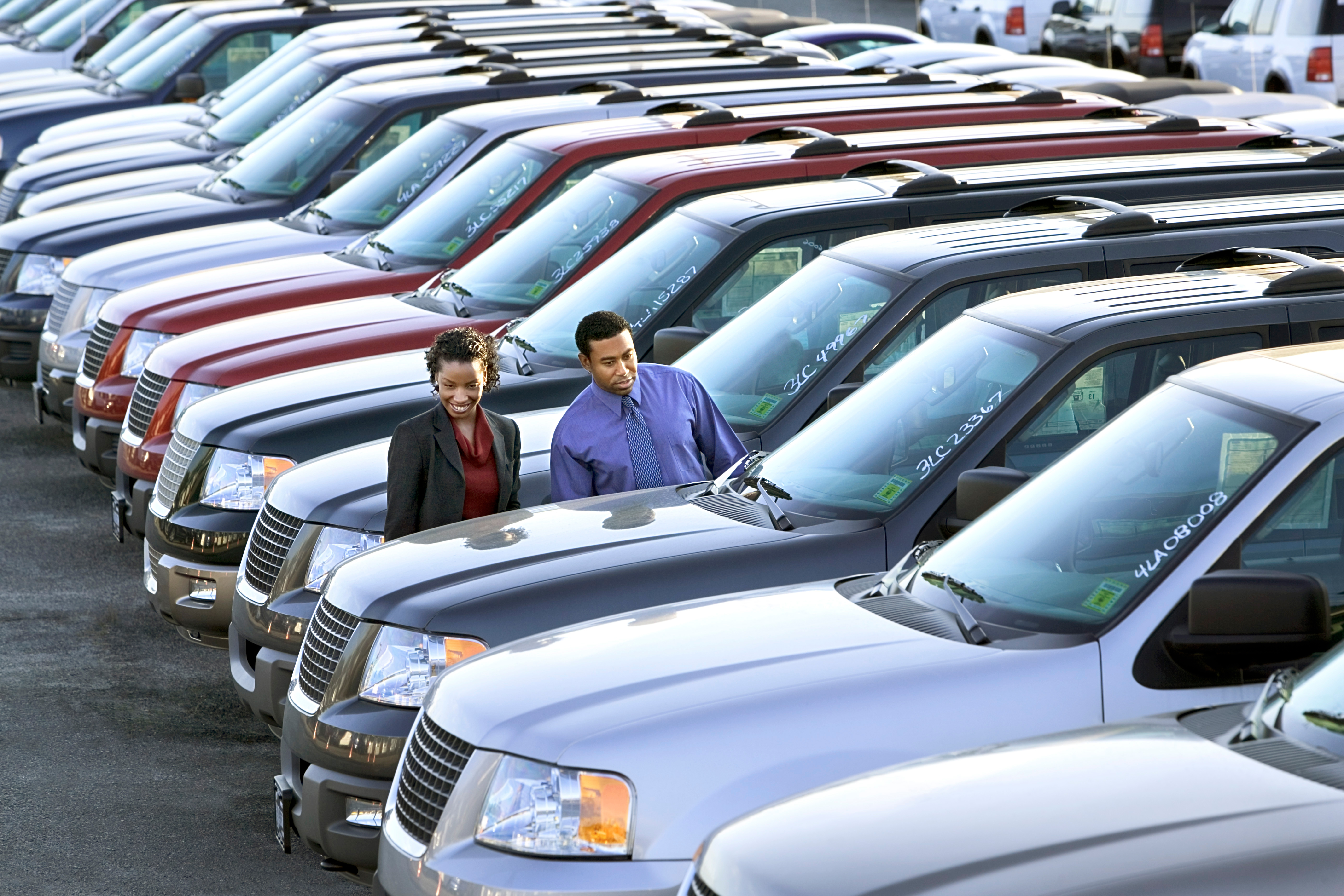 Woman and man look at cars for sale at dealership