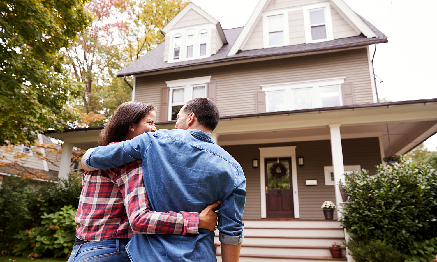 Woman and man hug in front of house