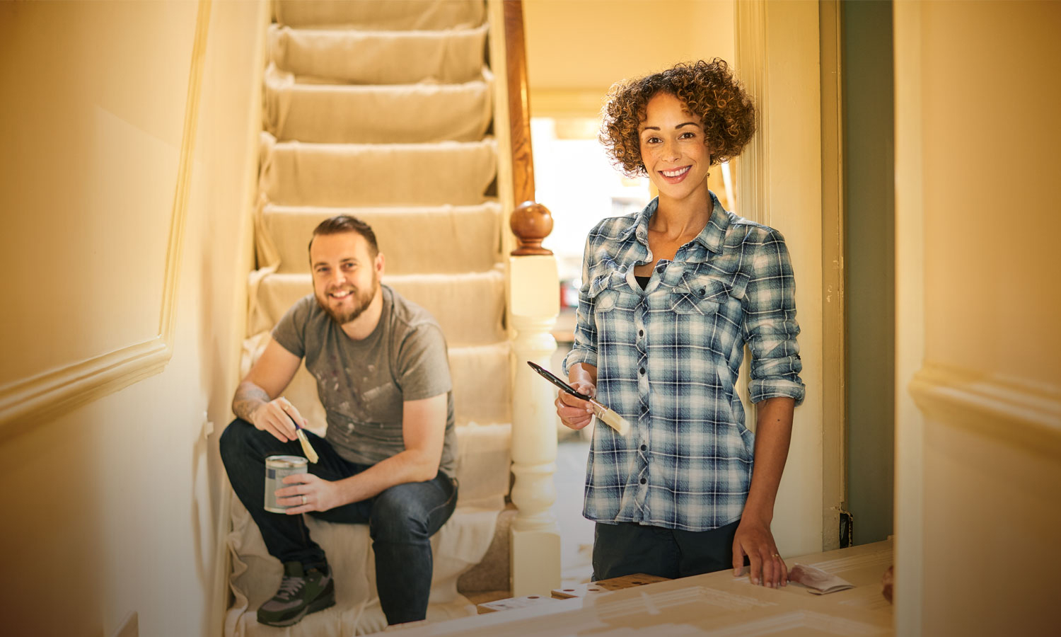 Man and woman painting stairway in house