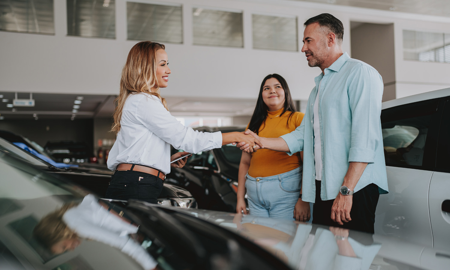 man shaking hands with salesperson surrounded by cars