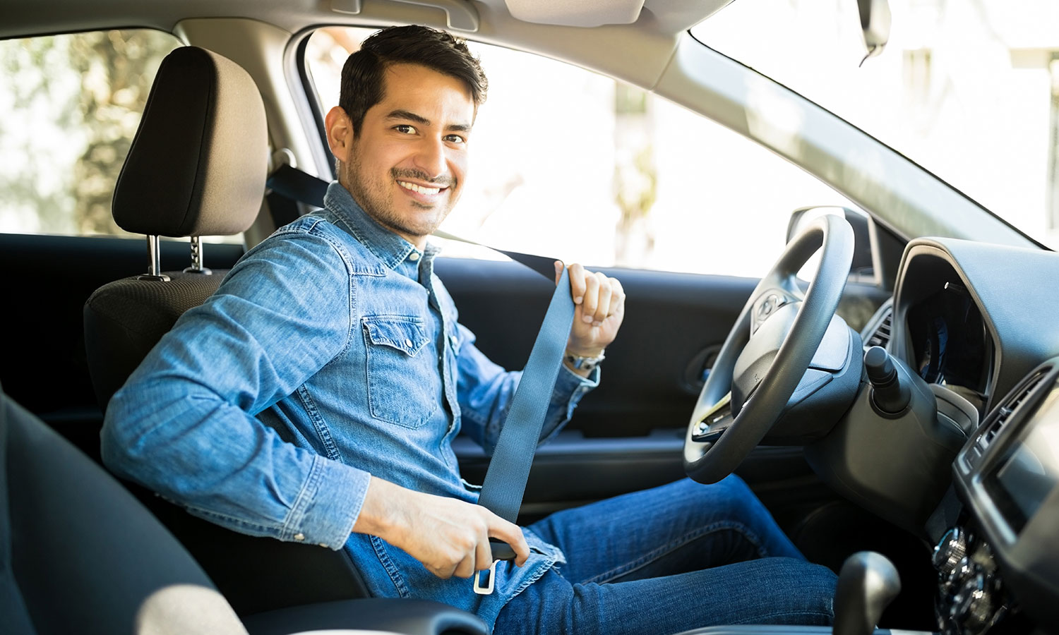 man sitting in the drivers seat of car and buckling his seatbelt