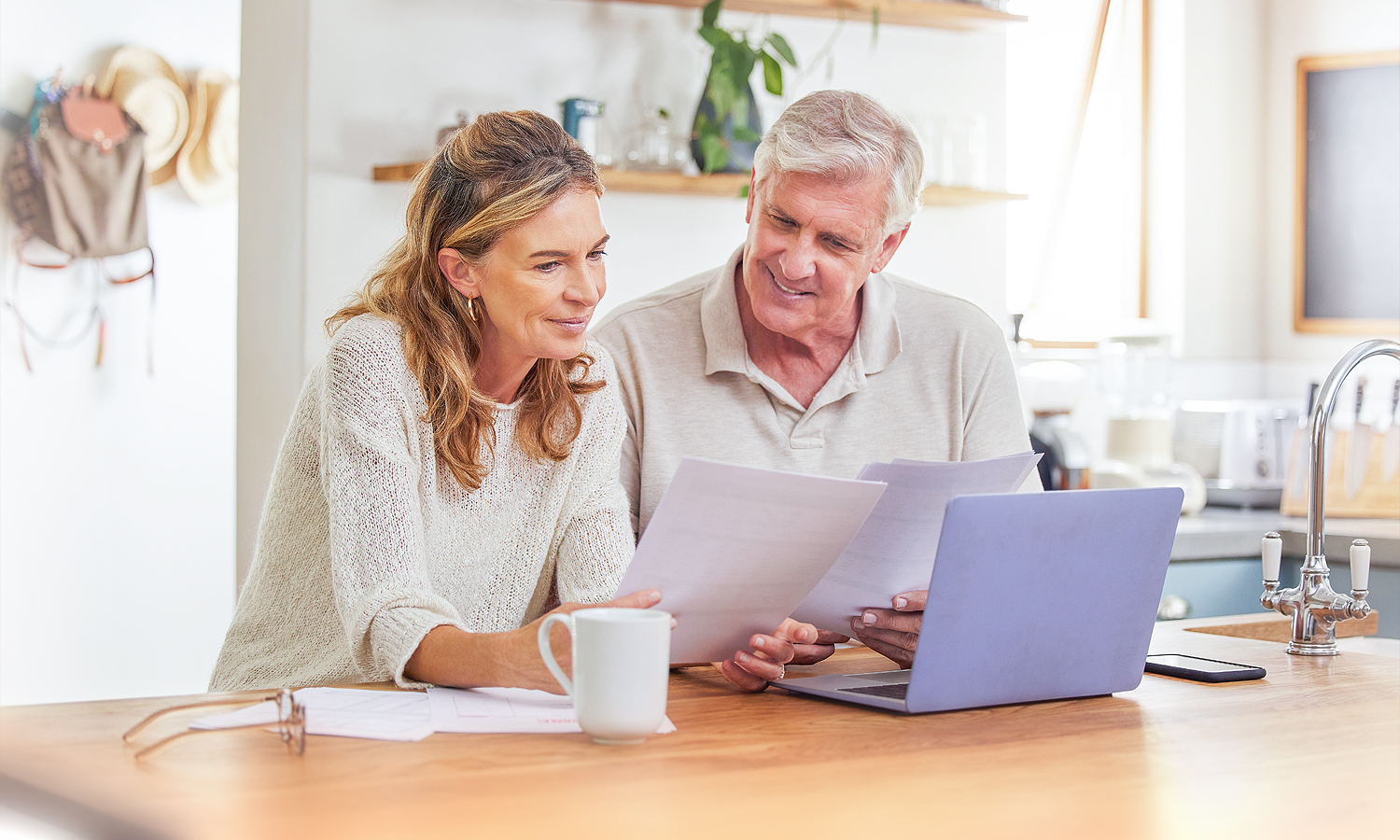 man and woman sitting at kitchen island looking at laptop