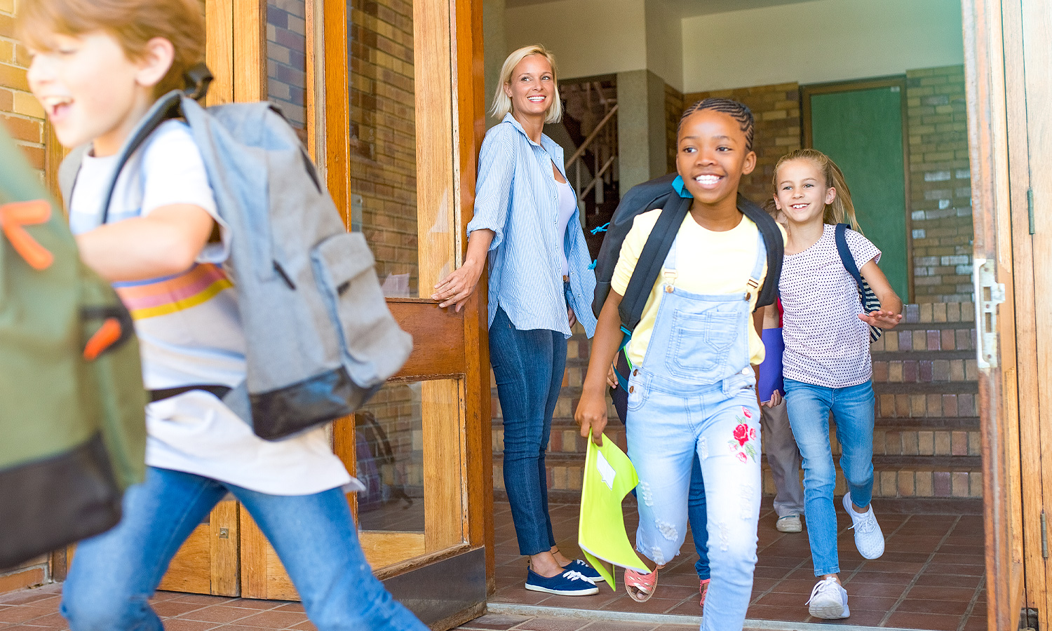 woman holding door open while children are running through