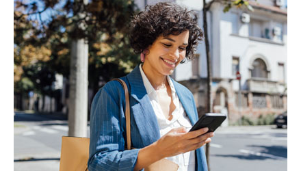 Woman checking smartphone while walking down the street